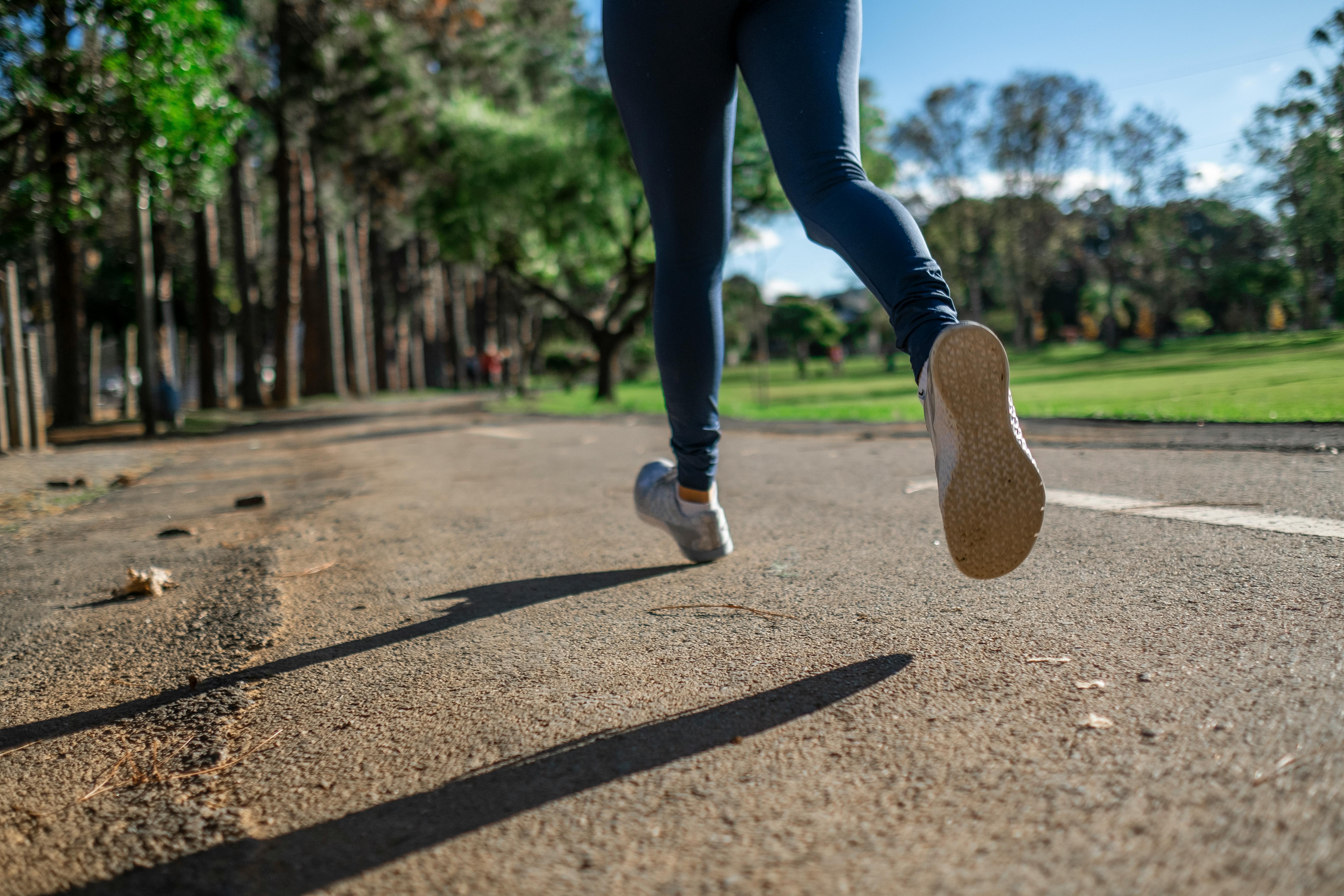Person jogging down the road on a sunny day.